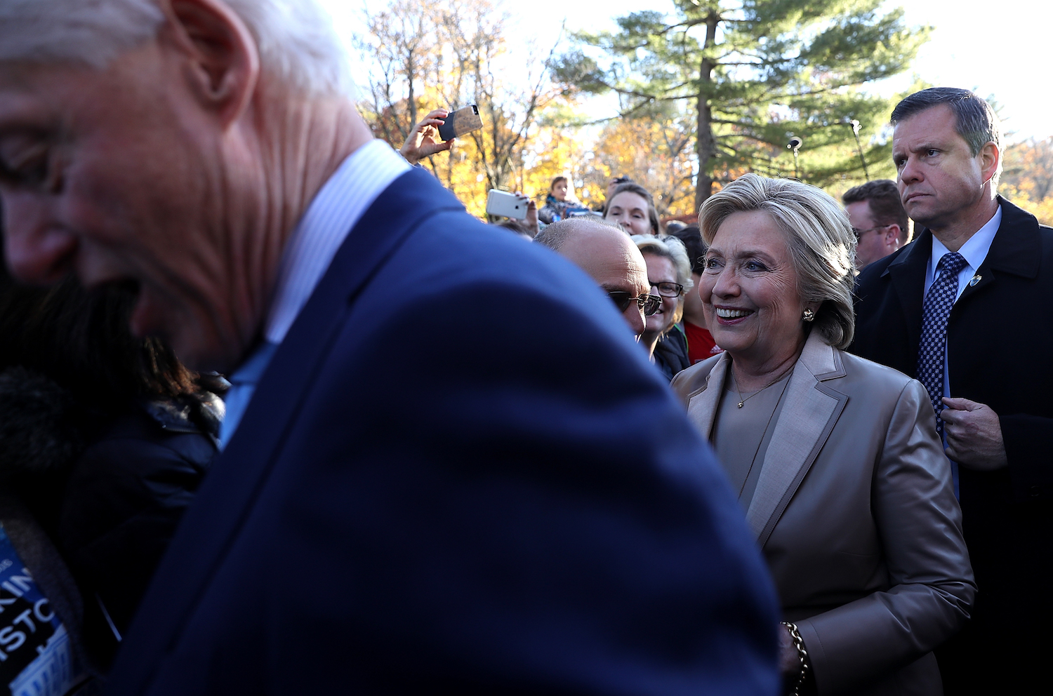 Hillary Clinton's husband overshadows her big voting moment with figure-hugging blue suit