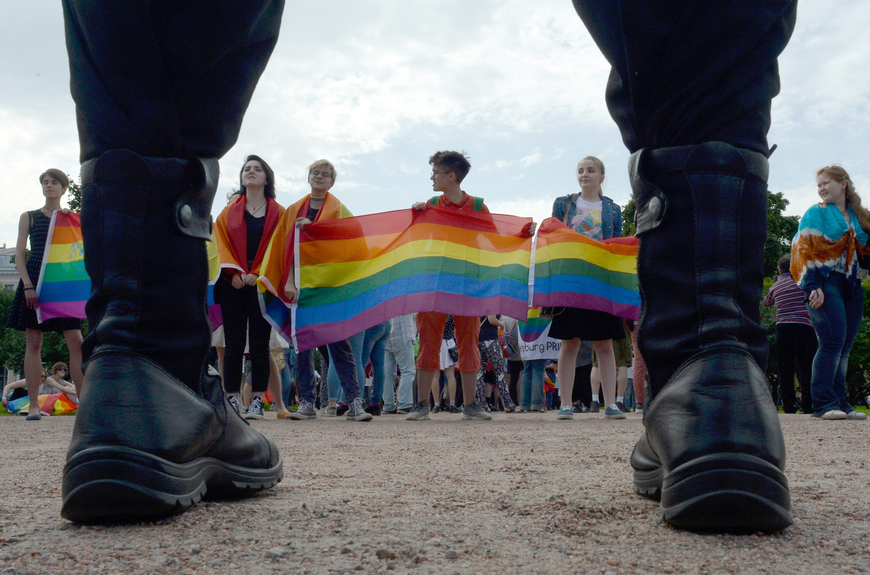 People wave rainbow flags during a pride rally in Saint Petersburg, on Agust 12, 2017 as police look on.