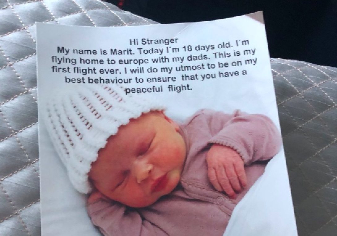 Cute gay couple hand plane passengers goodie bags to mark baby's first flight