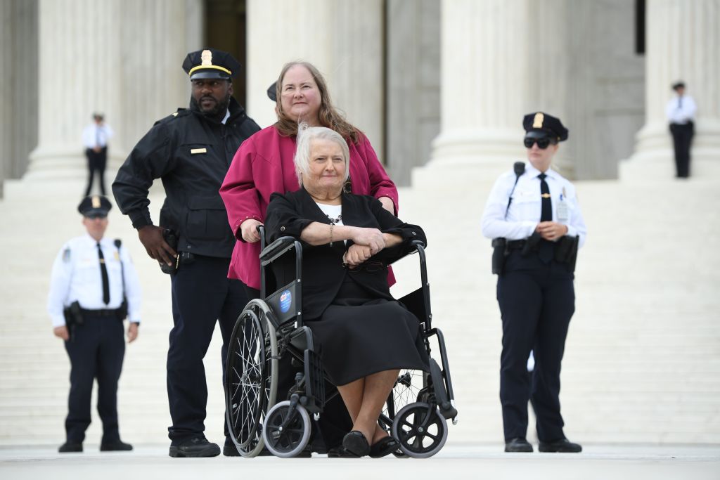 Transgender activist Aimee Stephens,with her wife behind, sits in her wheelchair outside the US Supreme Court in Washington, DC, October 8, 2019