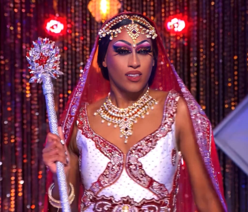 Priyanka holding her sceptre in a red-tipped sari