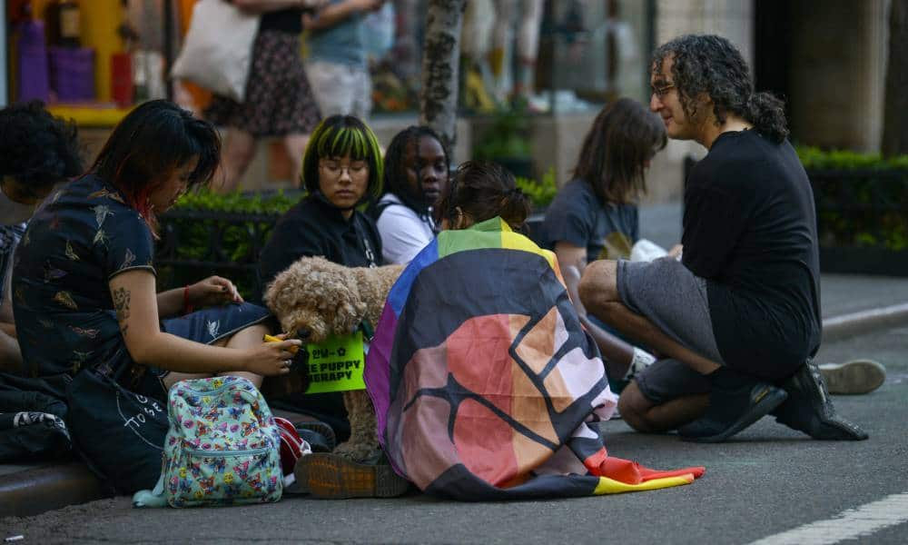 People gather to protest at the one year anniversary of the Black Lives Matter Stonewall Protests Pride flag