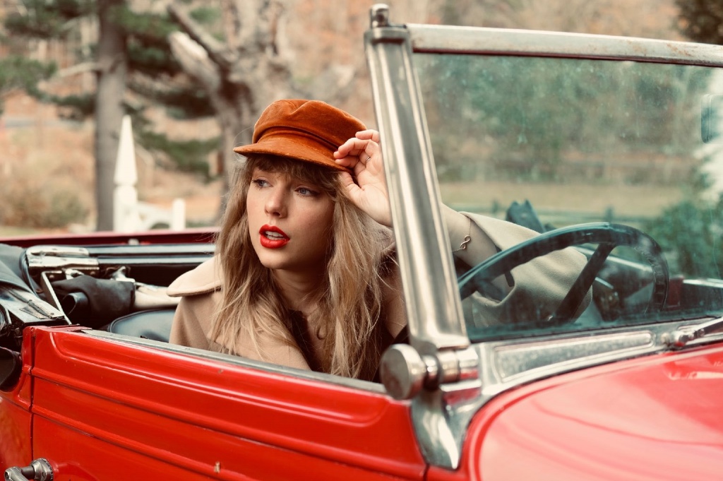Taylor Swift sitting in a car in a promotional image for Red (Taylor