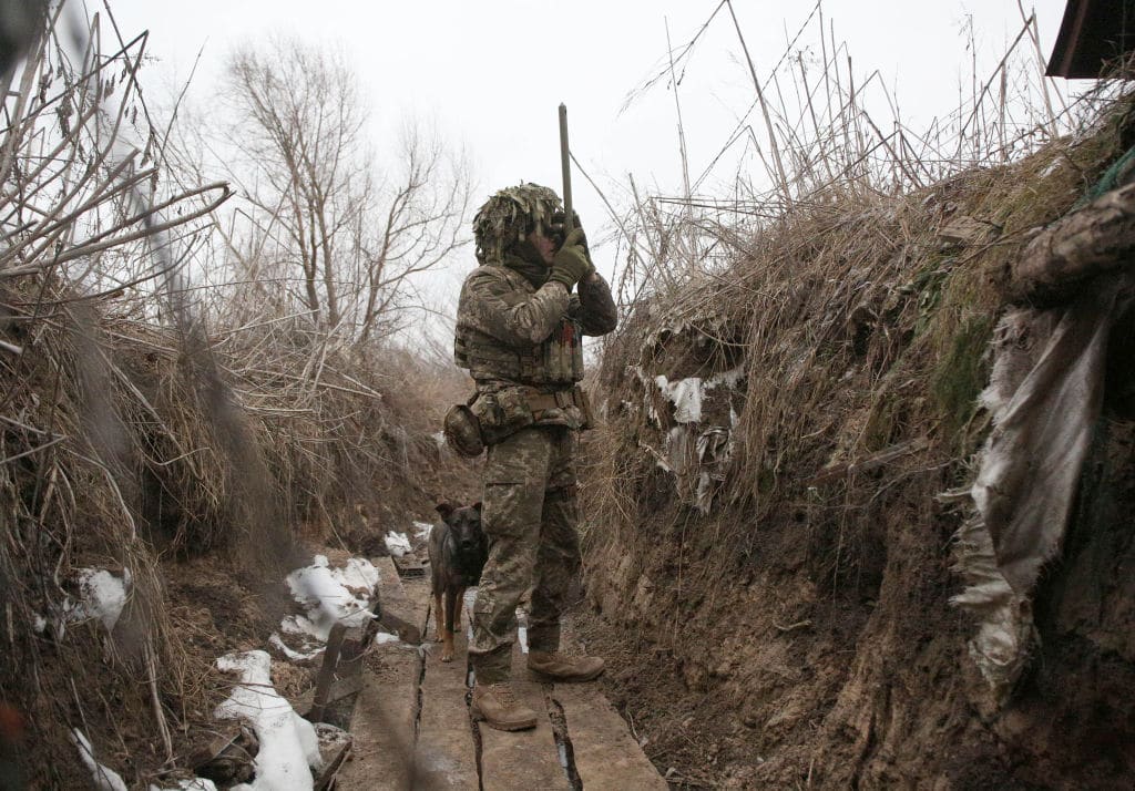 An Ukrainian Military Forces serviceman, watches through spyglass in a trench on the frontline with Russia-backed separatists near to Avdiivka, southeastern Ukraine, on January 9, 2022. 