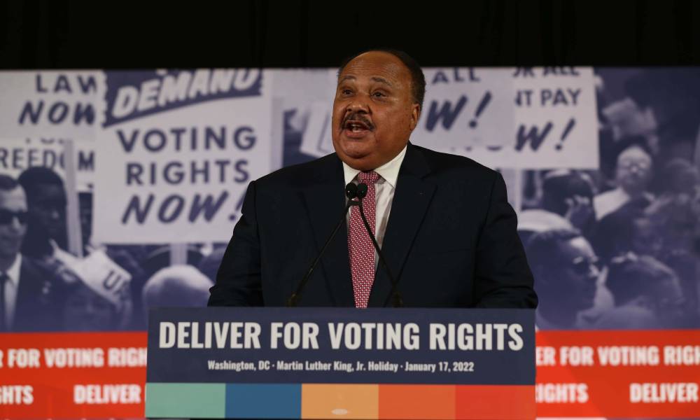Martin Luther King III stands at a podium with the words &quot;deliver for voting rights&quot; on it