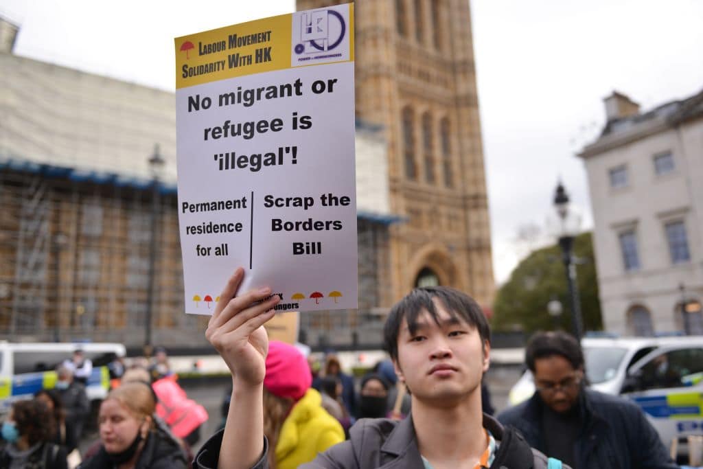 Demonstrator holds a placard that says No Migrant Or Refugee Is Illegal during the rally. 