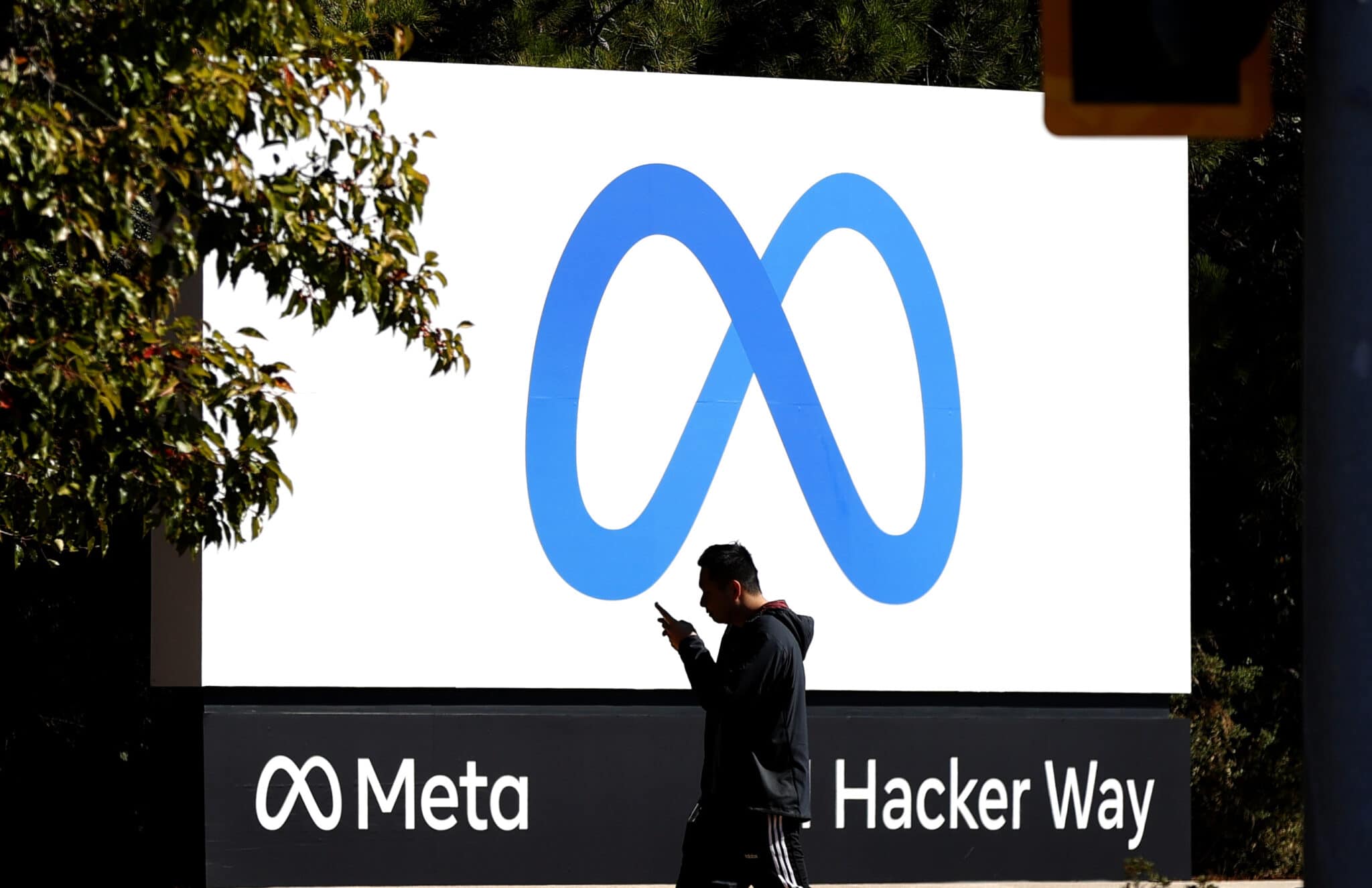 A person walks past a billboard showing the Meta logo