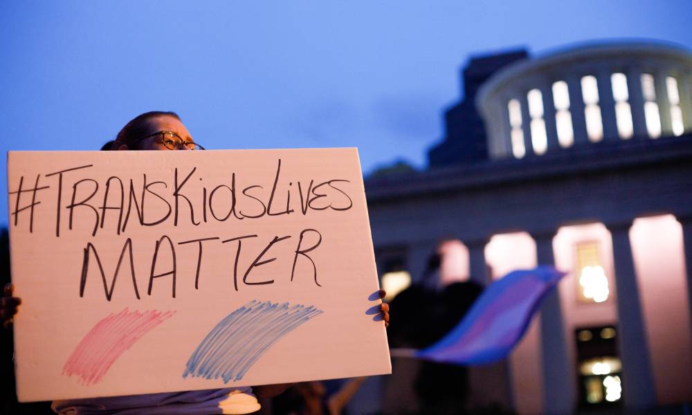 A transgender rights advocate holds a sign that reads 