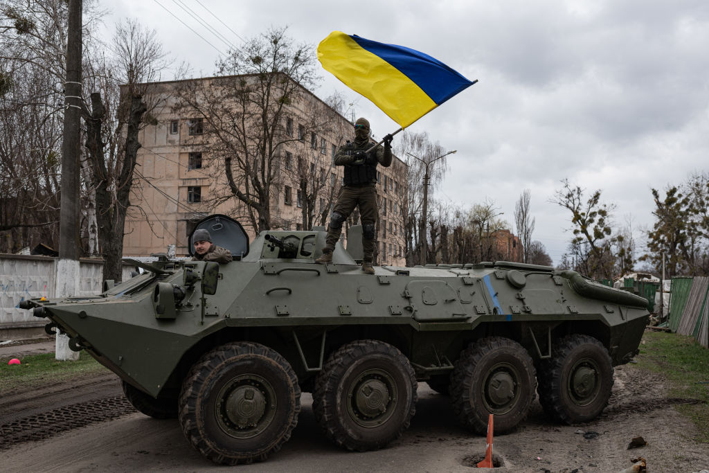 Ukrainian soldier waves Ukrainian national flag while standing on top of an armoured personnel carrier (APC) on April 8, 2022 in Hostomel, Ukraine.