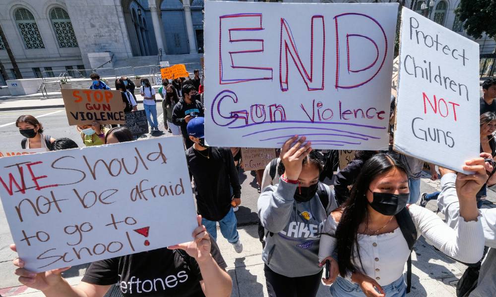 Students participate in a school walk-out and protest in front of City Hall to condemn gun violence. One person holds up a sign reading 