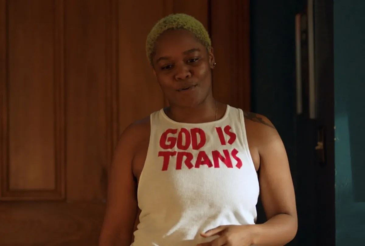 CG wearing a t-shirt that reads &quot;God is Trans&quot; in Queer as Folk. 