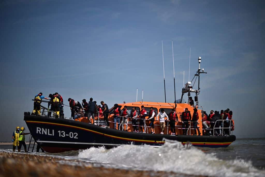 Migrants, picked up at sea attempting to cross the English Channel, are helped ashore from an Royal National Lifeboat Institution