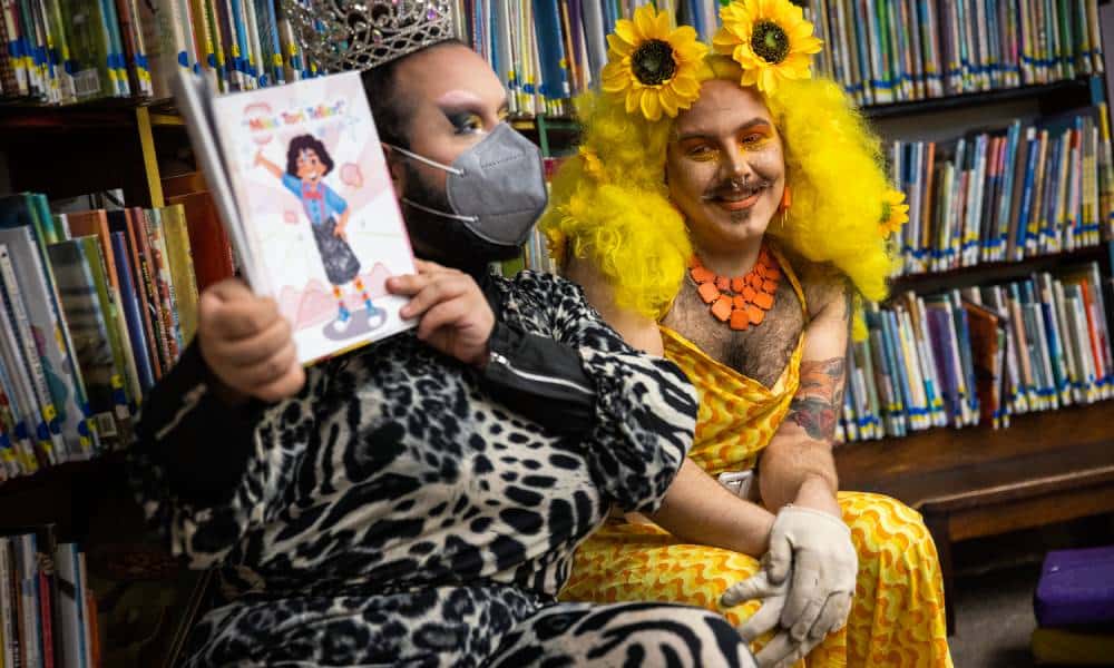 One drag performer wears a monochromatic animal print outfit, sparkly face mask and silver crown as they read from a children