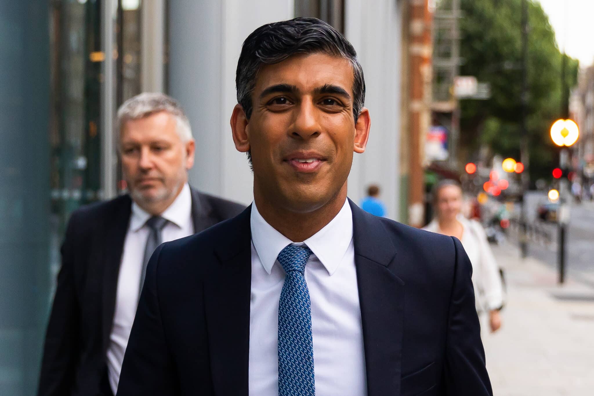 Rishi Sunak walks towards the camera in a suit
