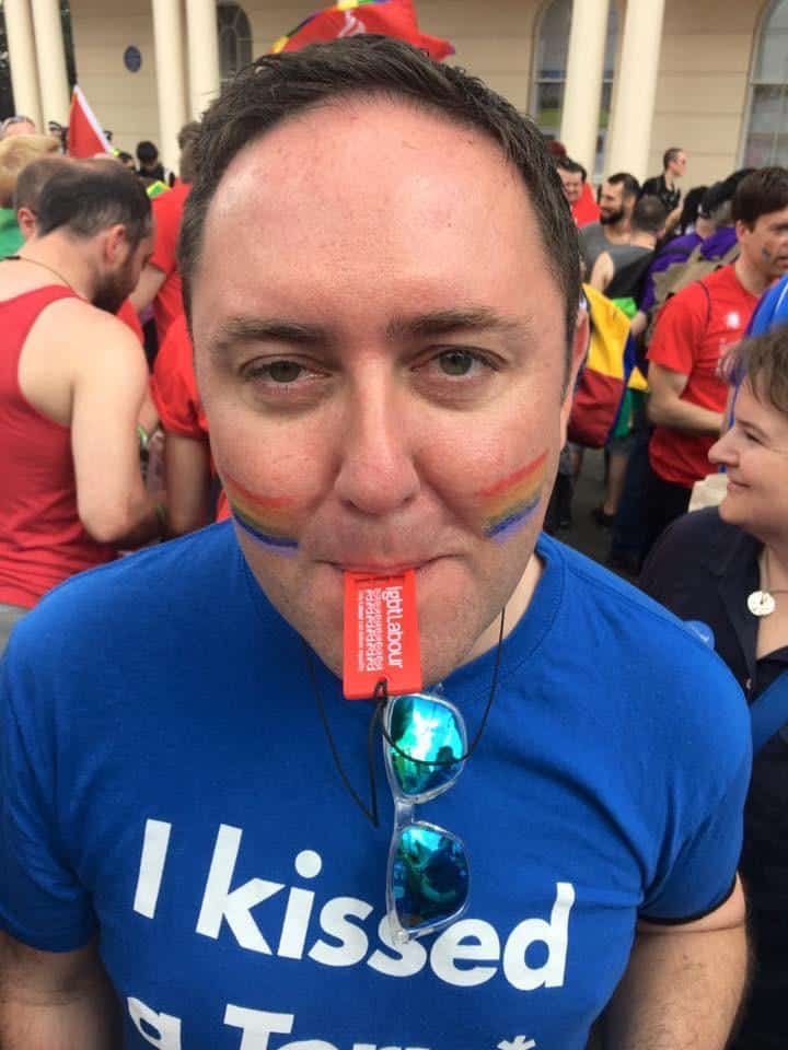 Colm Howard-Lloyd wearing a t-shirt that reads &quot;I kissed a Tory&quot; at a Pride event. He has rainbow colours painted on his face.