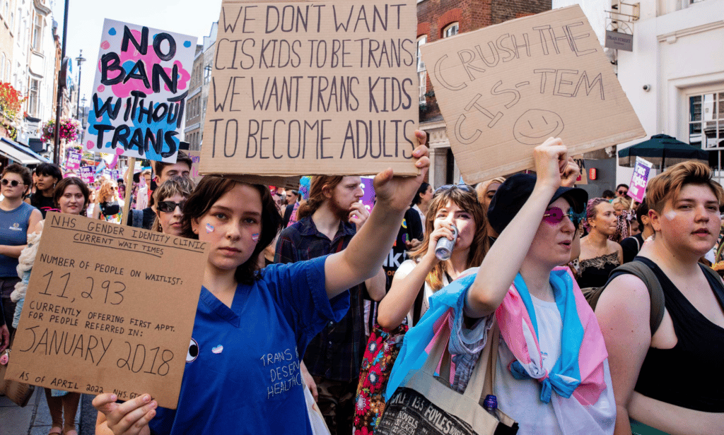 People gather together to highlight the lengthy wait times trans people face accessing gender-affirming healthcare through the NHS