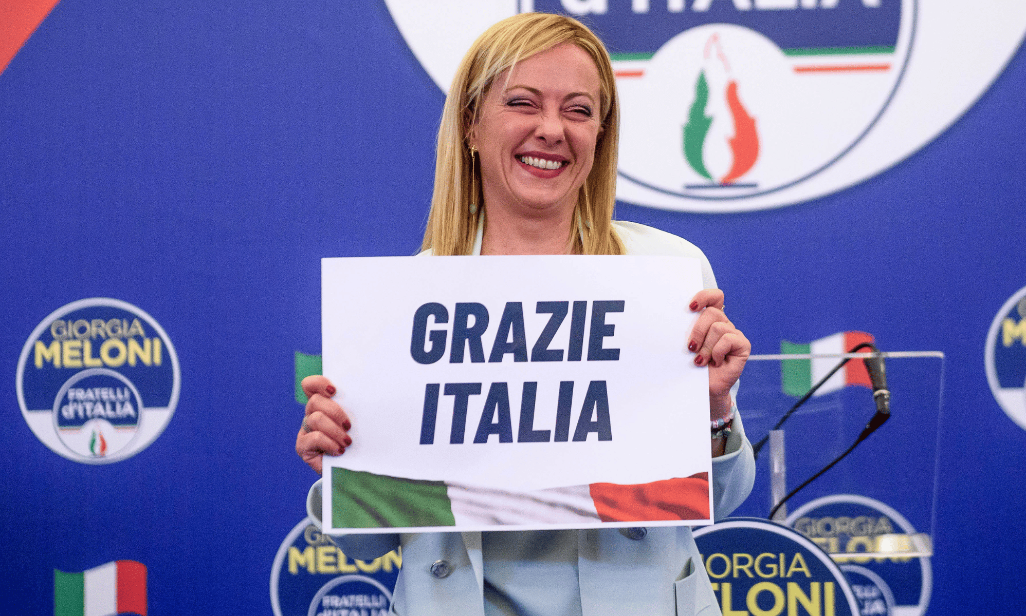 Giorgia Meloni holds up a sign reading 