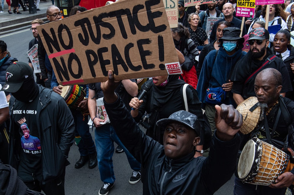 Protesters hold a sign that reads &quot;no justice, no peace&quot; during a march in London