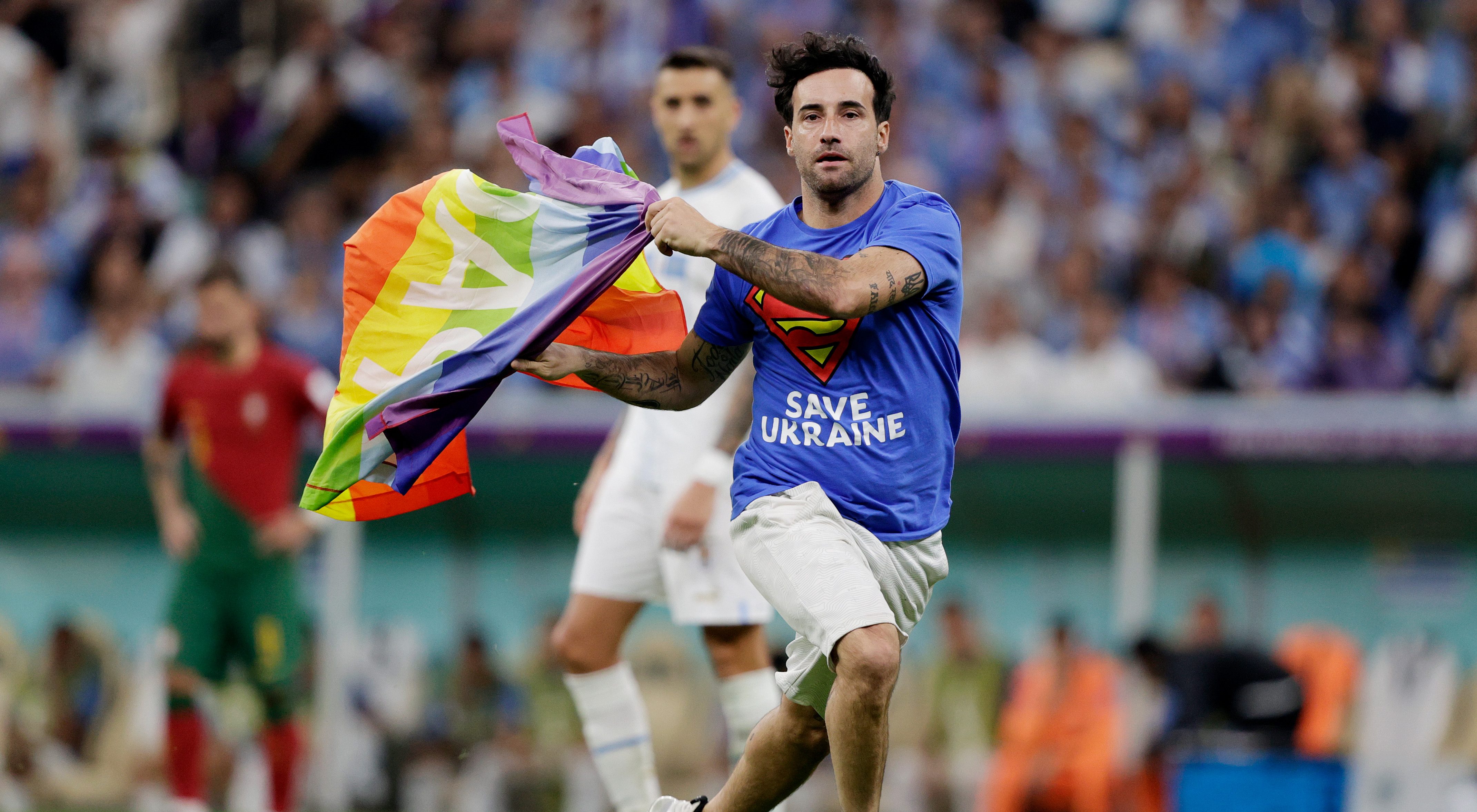 Heroic activist Mario Ferri Falco runs onto the pitch holding a rainbow Pride flag on 28 November during the World Cup match between Portugal v Uruguay at the Lusail Stadium in Qatar