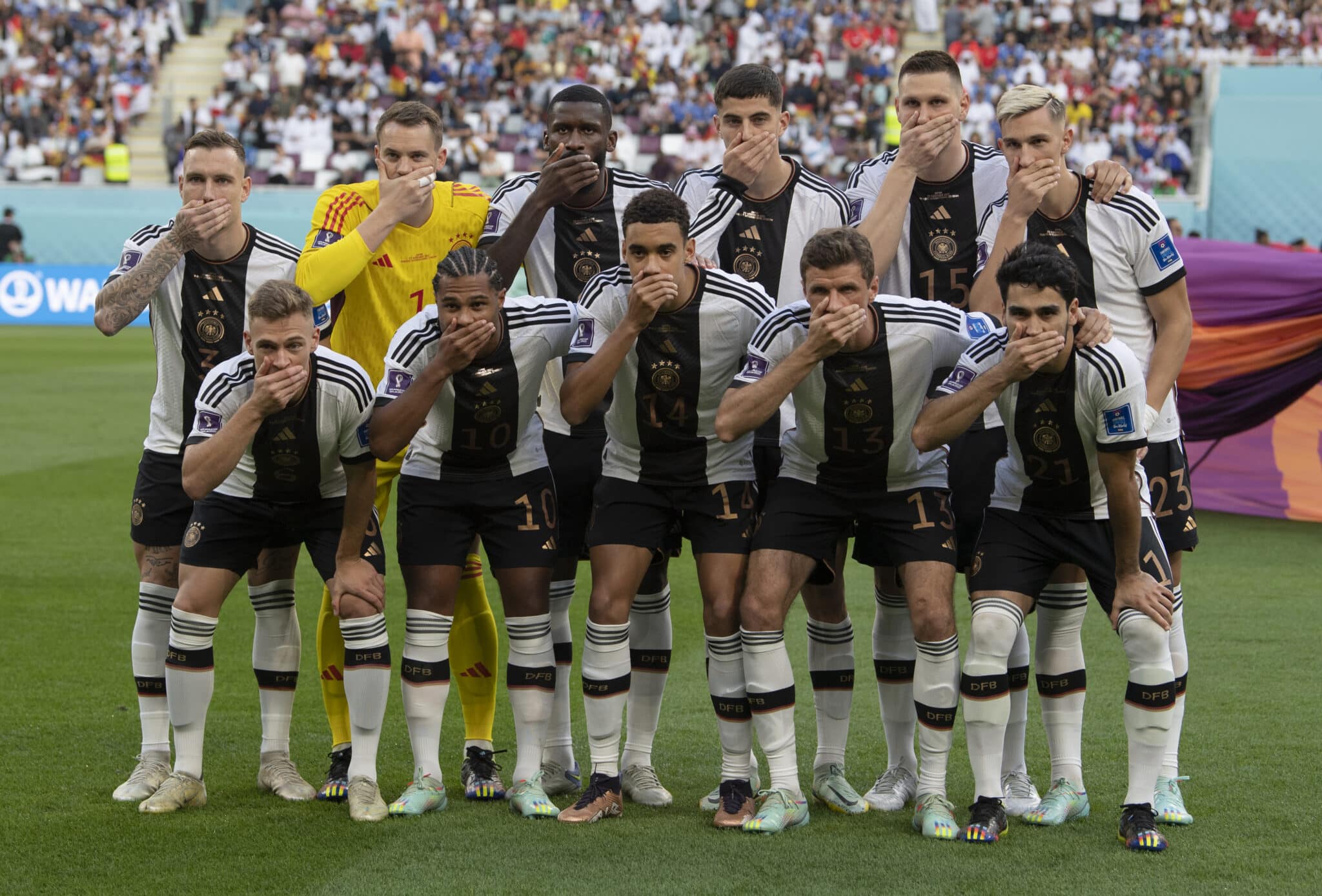 German football team members pose with their hands covering their mouths as they line up for the team photo ahead of the FIFA World Cup Qatar match between Germany and Japan