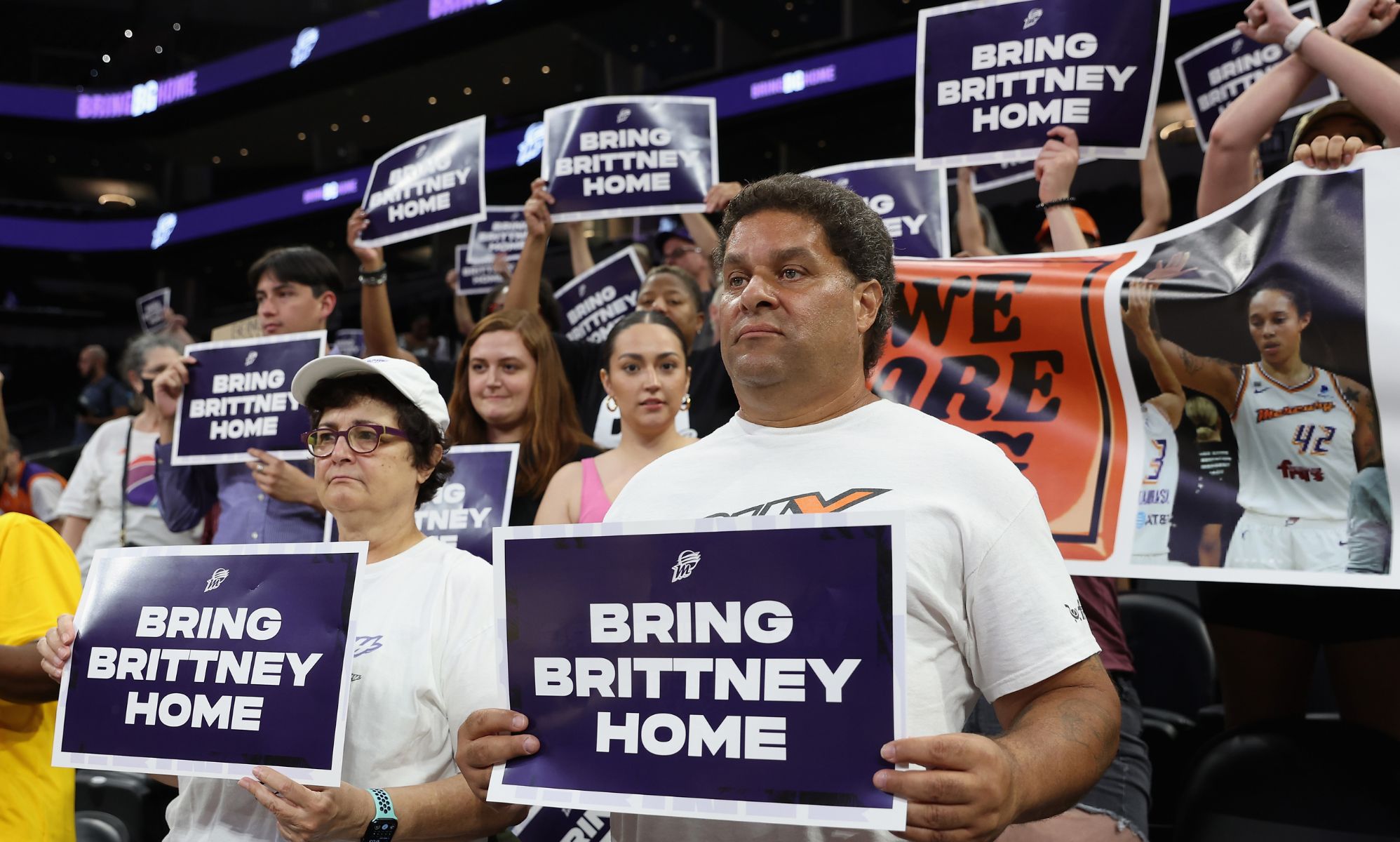 People hold up signs reading 
