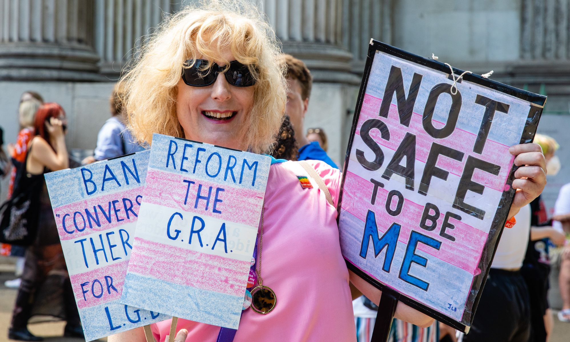 A protestor holds up several cards, with one reading 