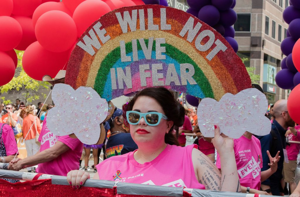 A woman stands under an elaborate, rainbow gay pride banner with the text &quot;We will not live in fear&quot;, during the 46th Lesbian, Gay, Bisexual and Transgender Pride March, New York City,