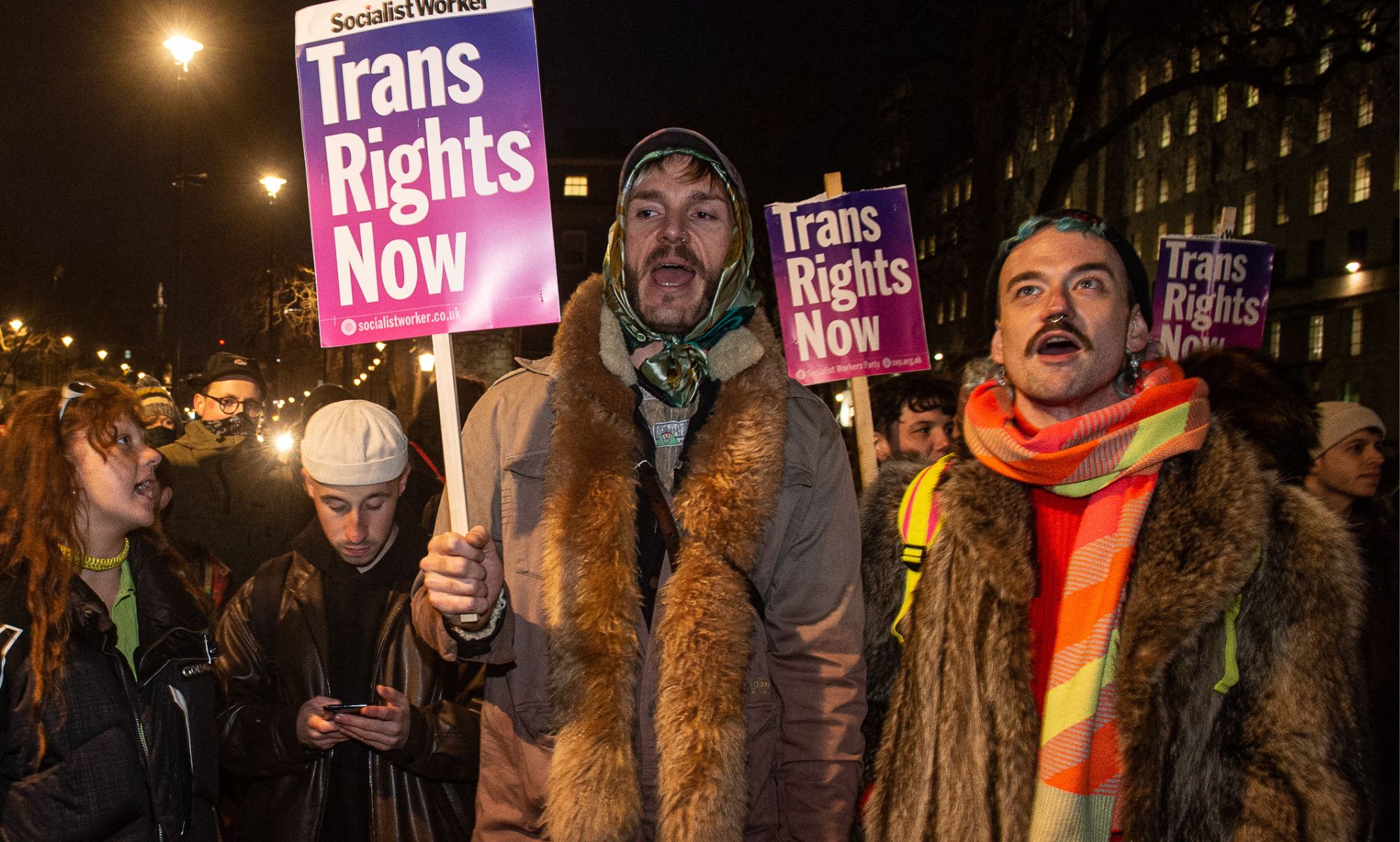 Protestors hold up signs reading 