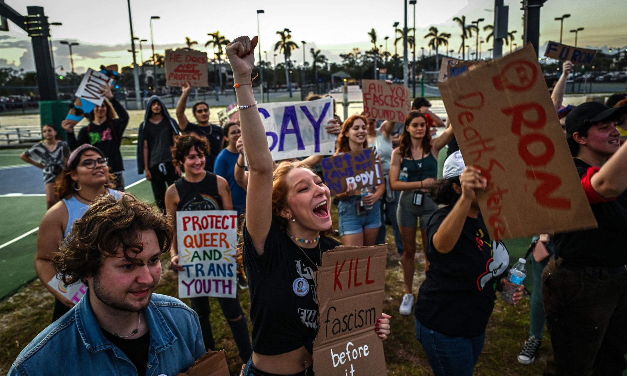 People hold up signs in support of the LGBTQ+ community as they protest against Florida governor Ron DeSantis, who championed the state