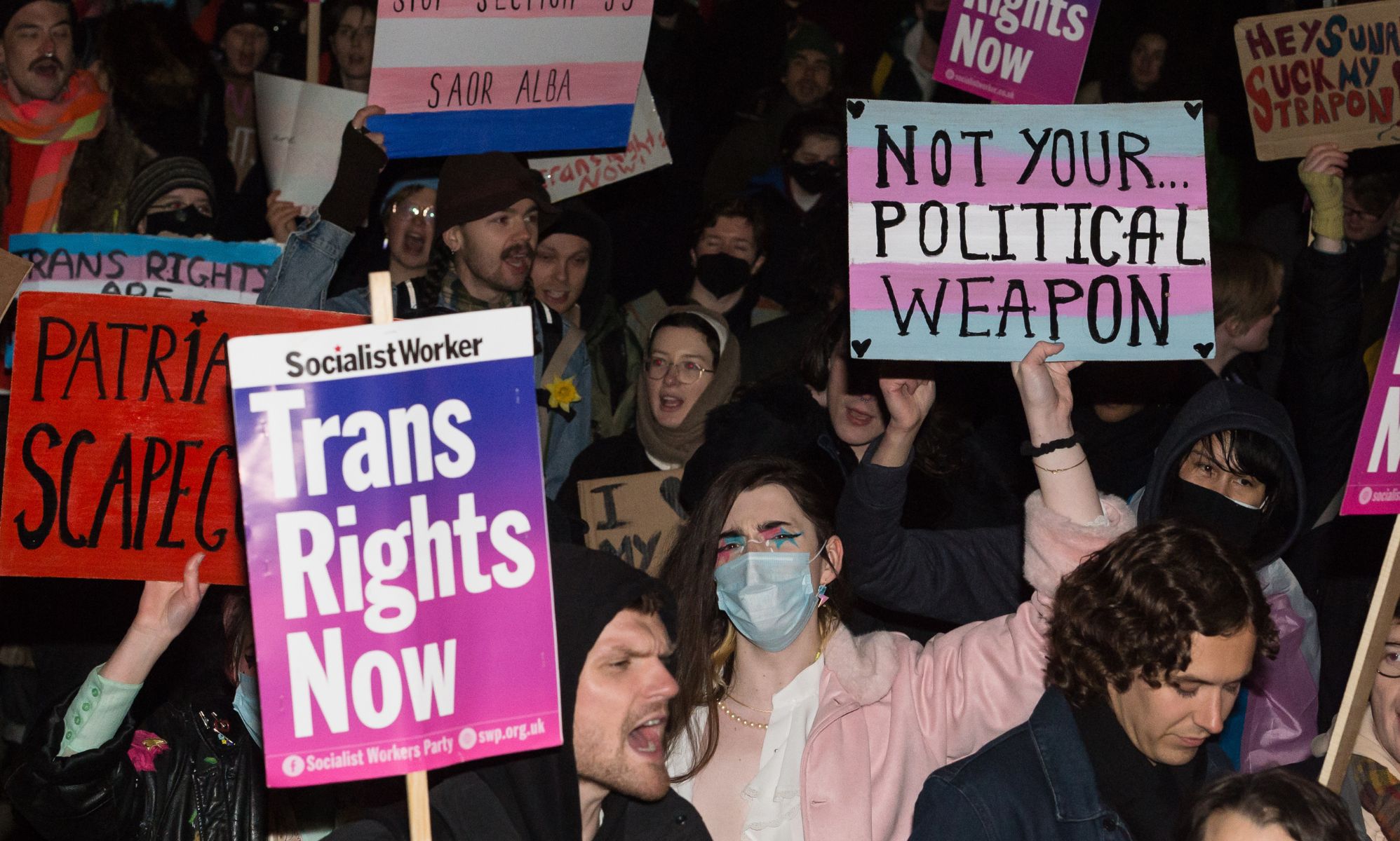 Transgender people and their supporters hold up signs and should as they demonstrate outside Downing Street against the UK government