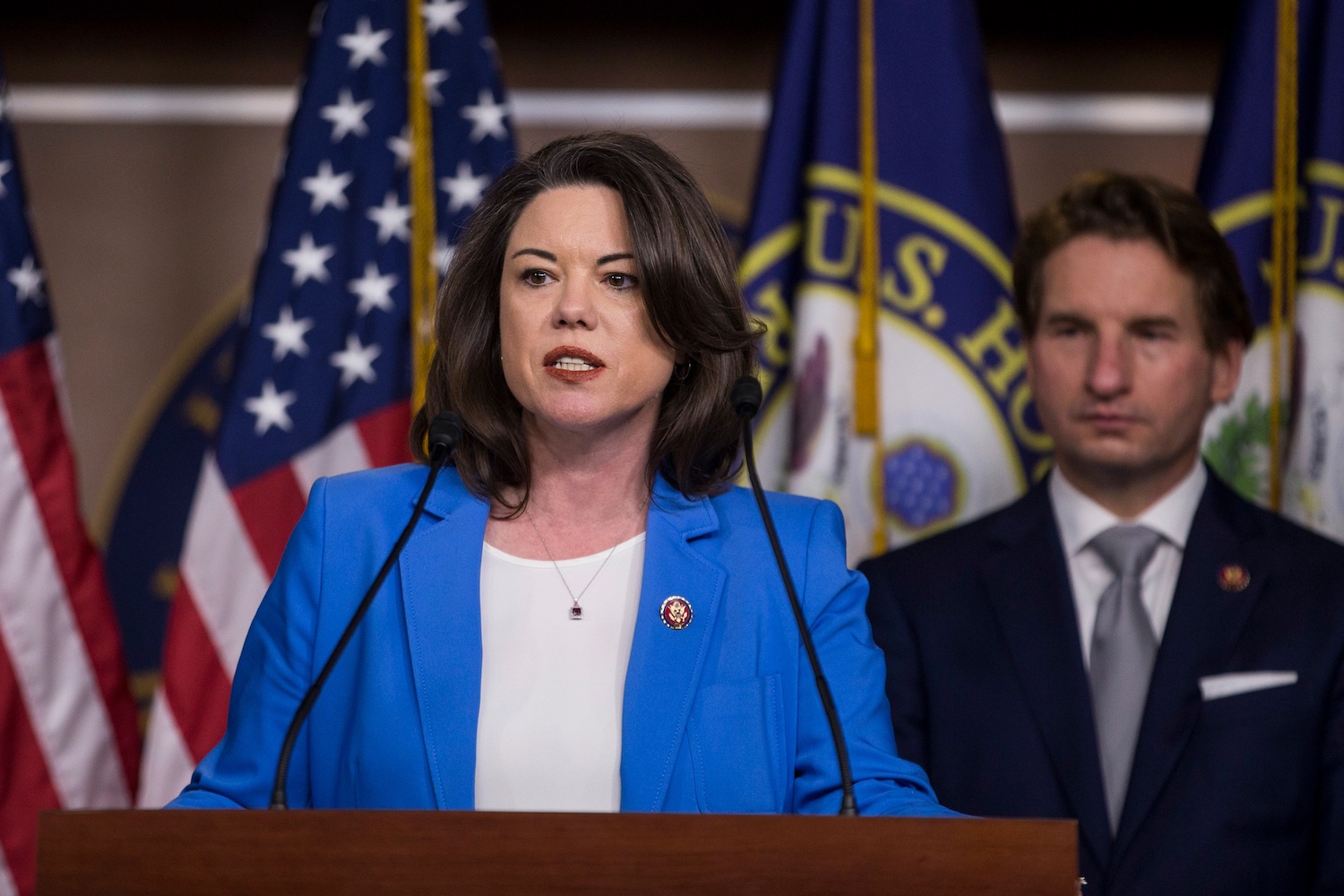 Angie Craig in a blue suit jacket and white shirt giving a speech in Congress.