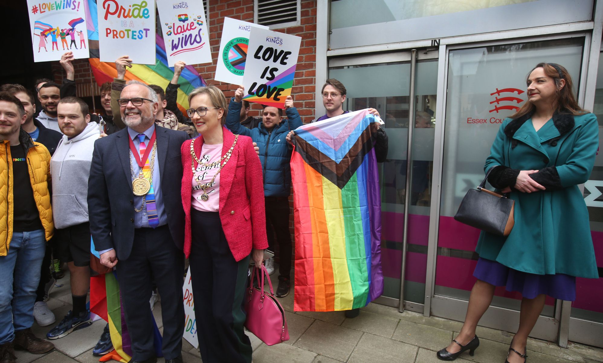 Several protestors holding up LGBTQ+ signs and flags.