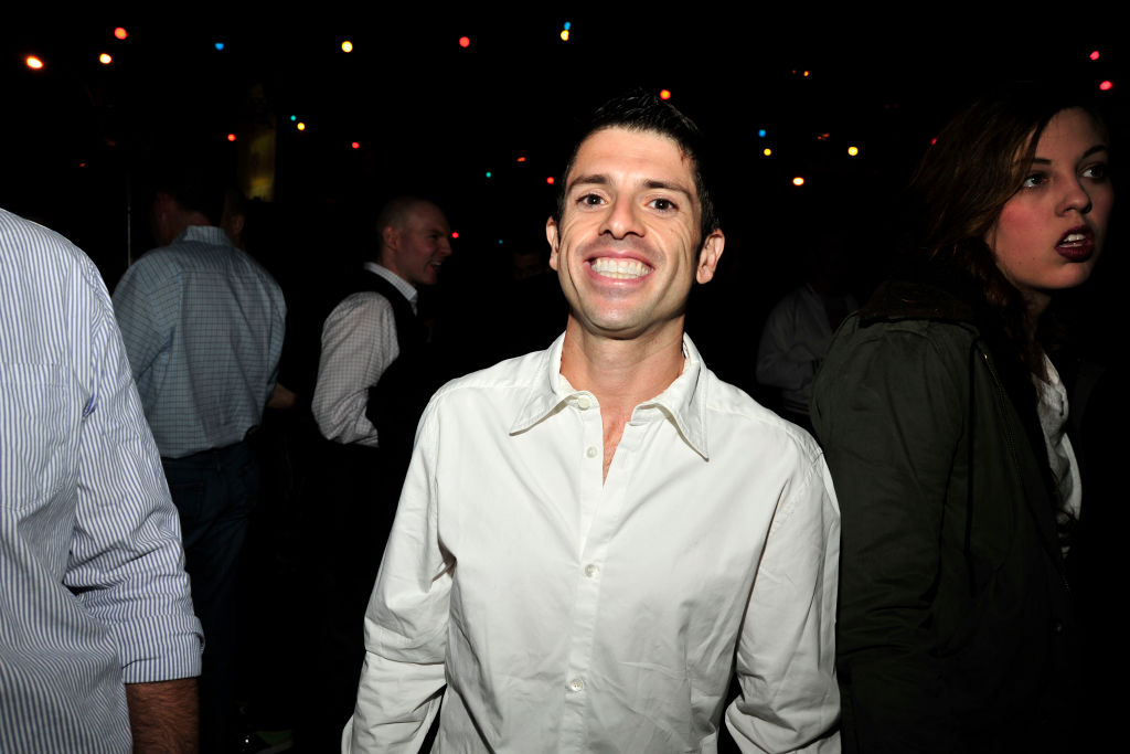 Joel Simkhai is wearing a white shirt and smiling for the camera.