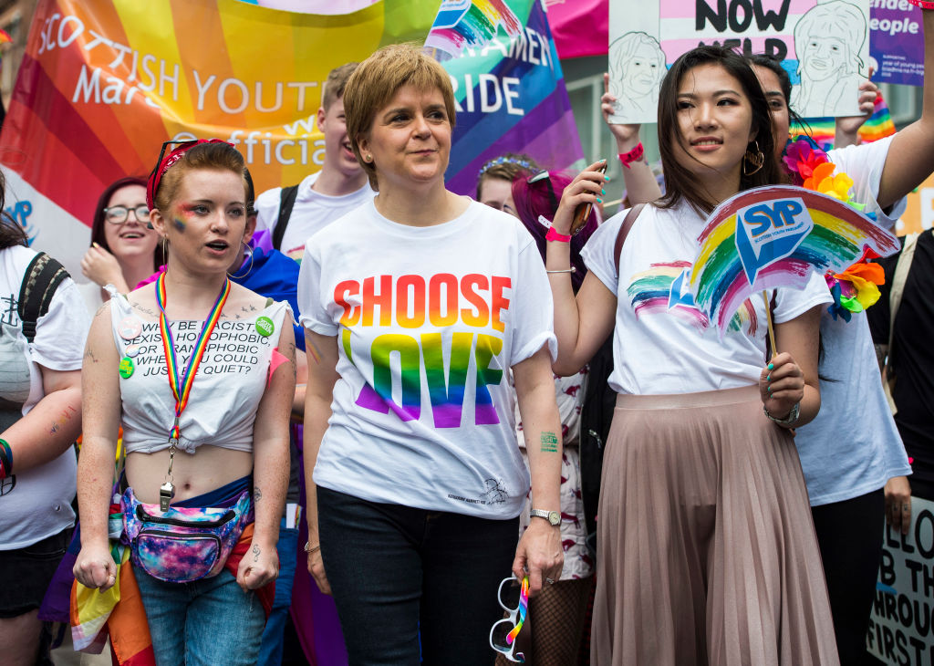 Nicola Sturgeon at the 2018 Pride Festival in Glasgow. She is pictured wearing a t-shirt that reads &quot;Choose Love&quot; in rainbow colours. Queer activists are pictured either side of her and in the background is a rainbow banner.