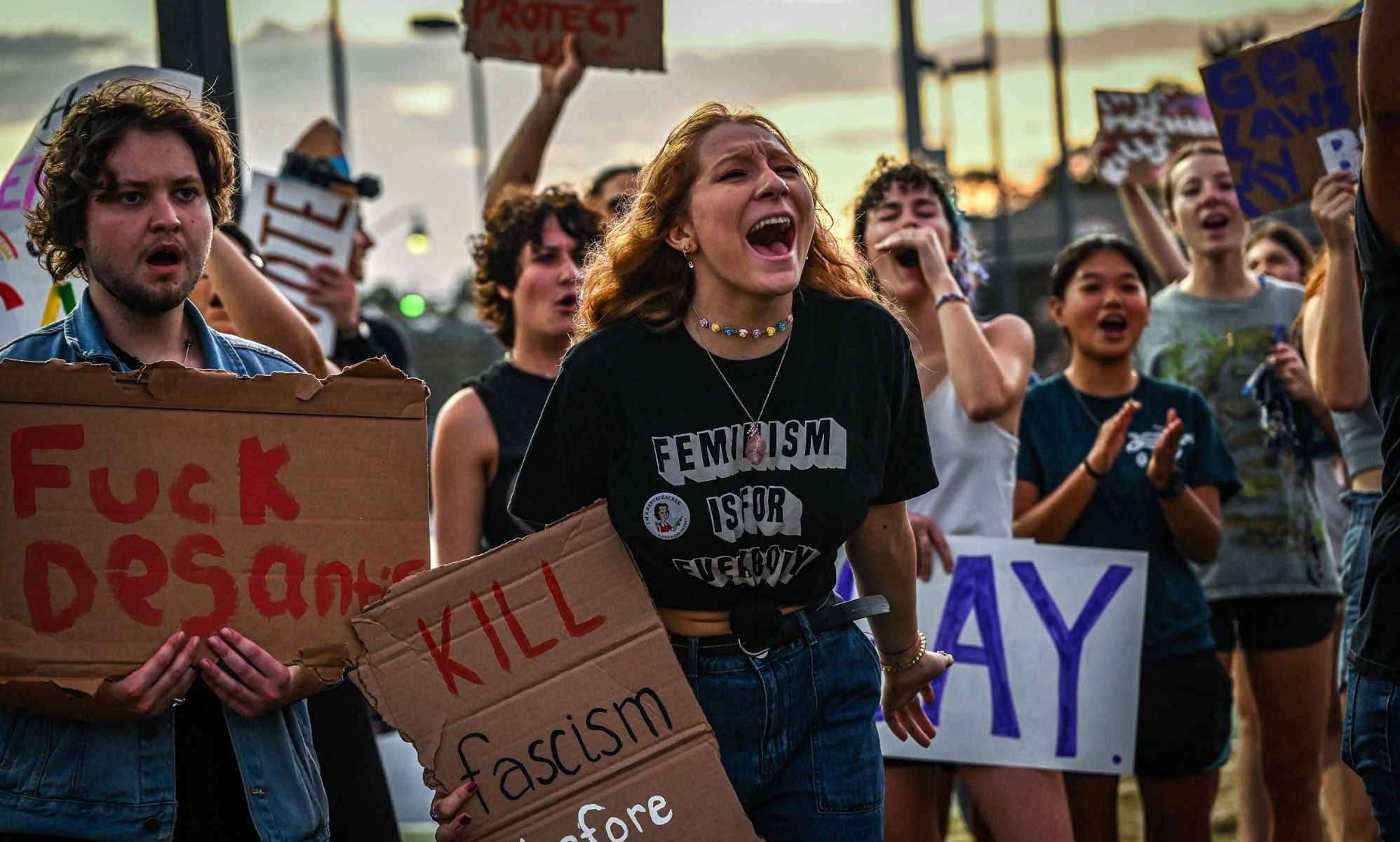 LGBTQ+ rights supporters protest against Florida Governor Ron Desantis, holding up signs criticising DeSantis and his support of the state