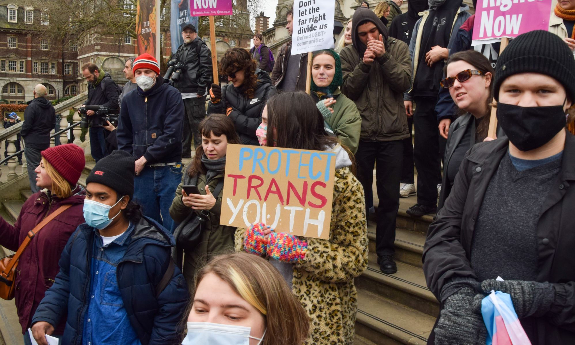 A person holds up a sign reading &quot;protect trans youth&quot; during a protest in support of the trans community