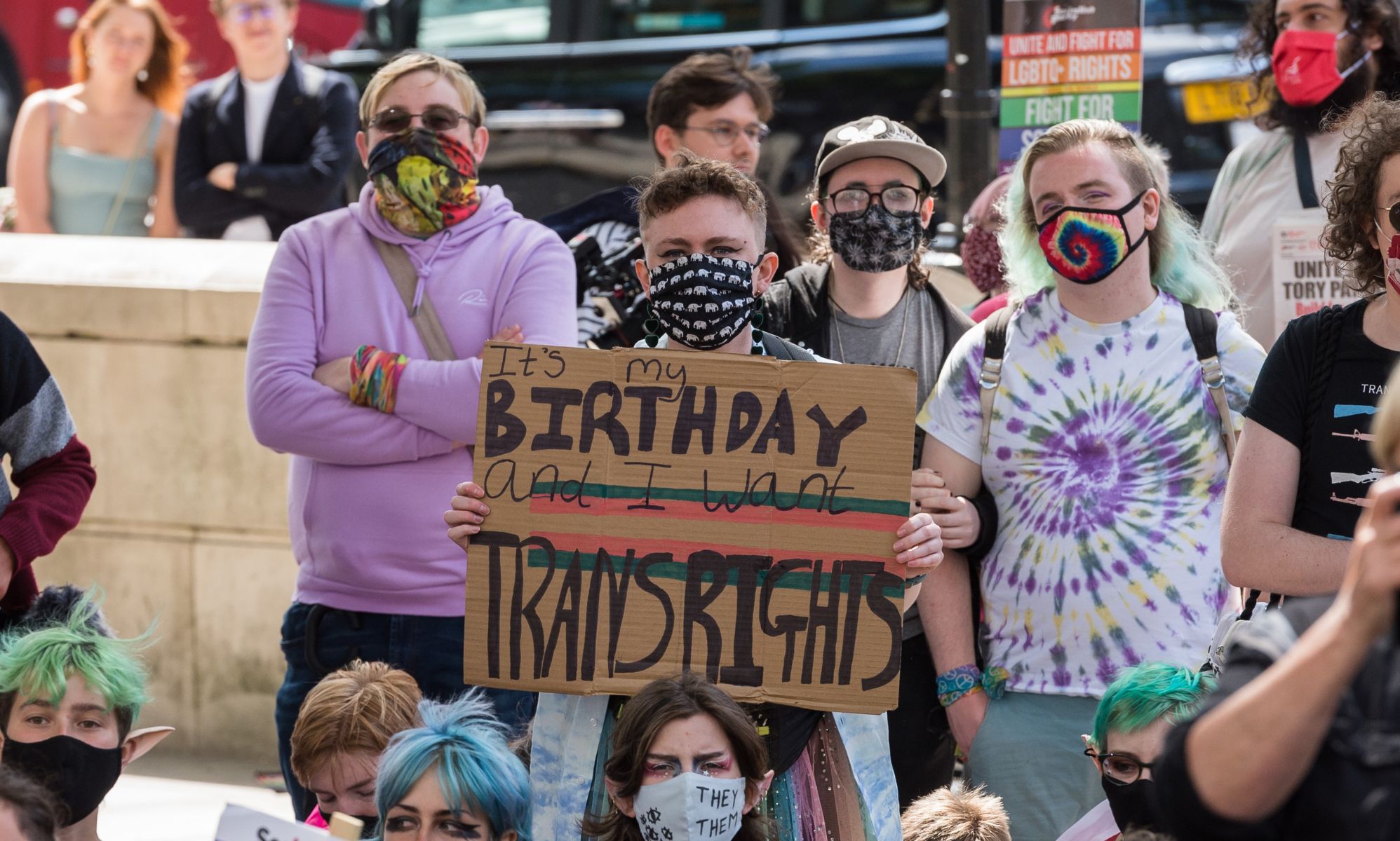 A person holds up a sign reading &quot;It