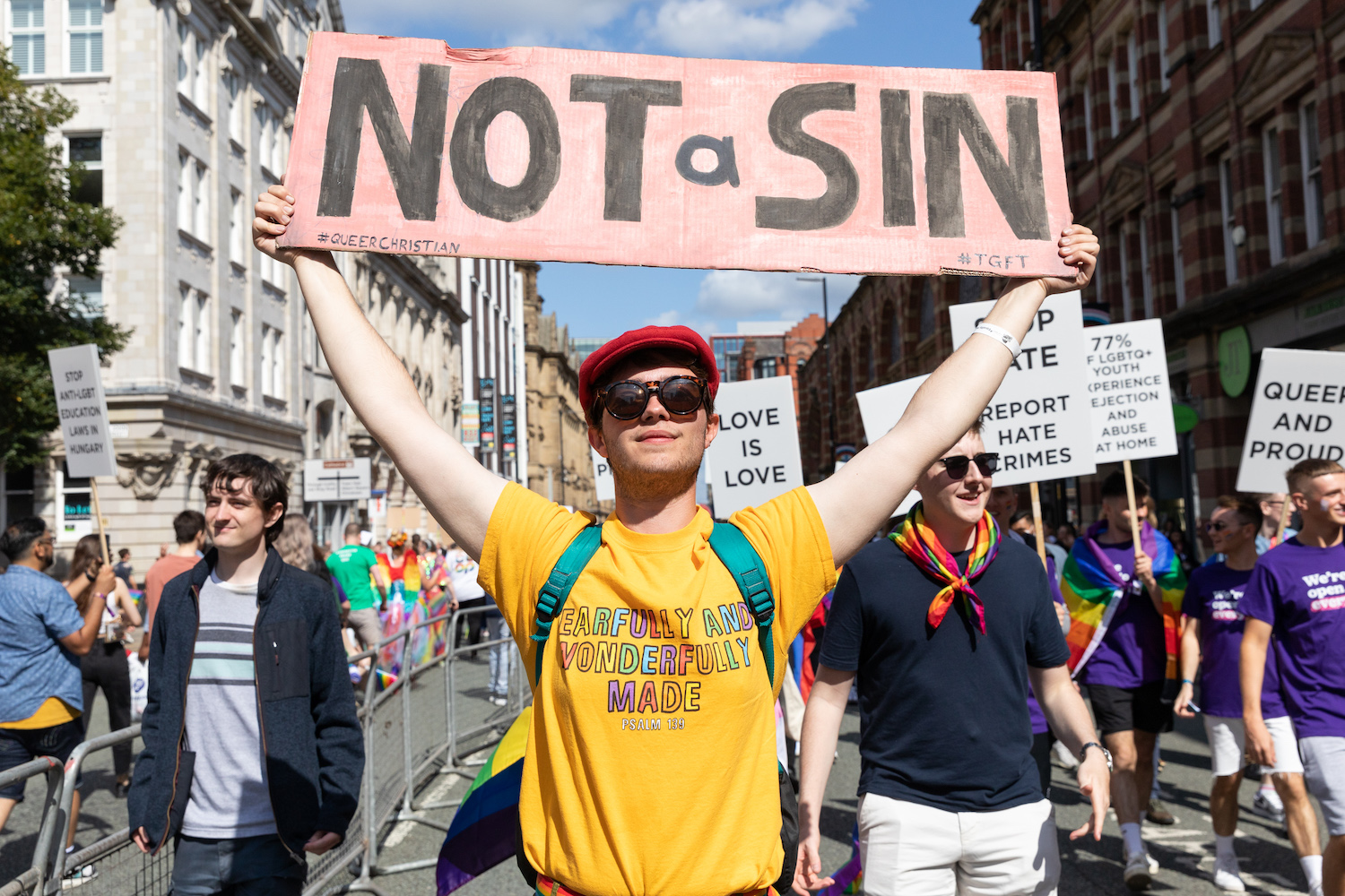 A person at Manchester Pride holding a sign that reads 