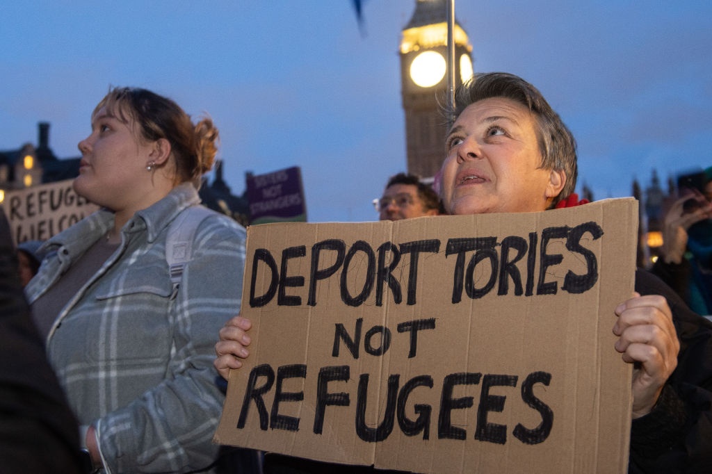 Hundreds of people protested in Parliament Square against the Illegal Migration Bill. A person is pictured holding a sign which says &quot;deport Tories not refugees&quot;.
