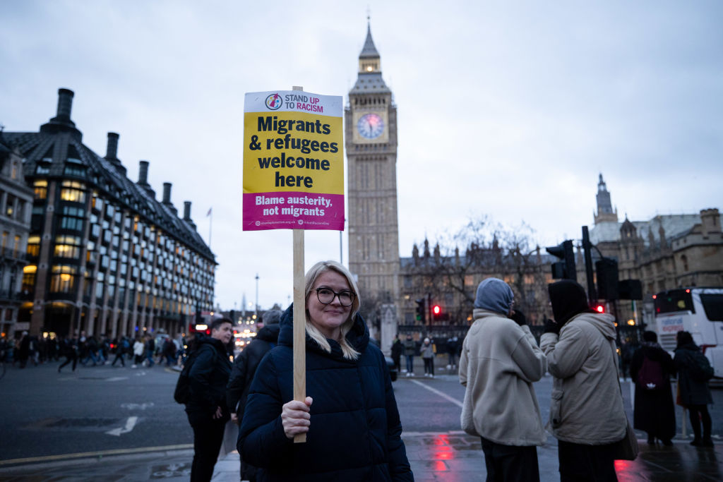 A protester is seen holding a placard during the rally at Parliament Square. The sign says &quot;Migrants and Refugees welcome here&quot;