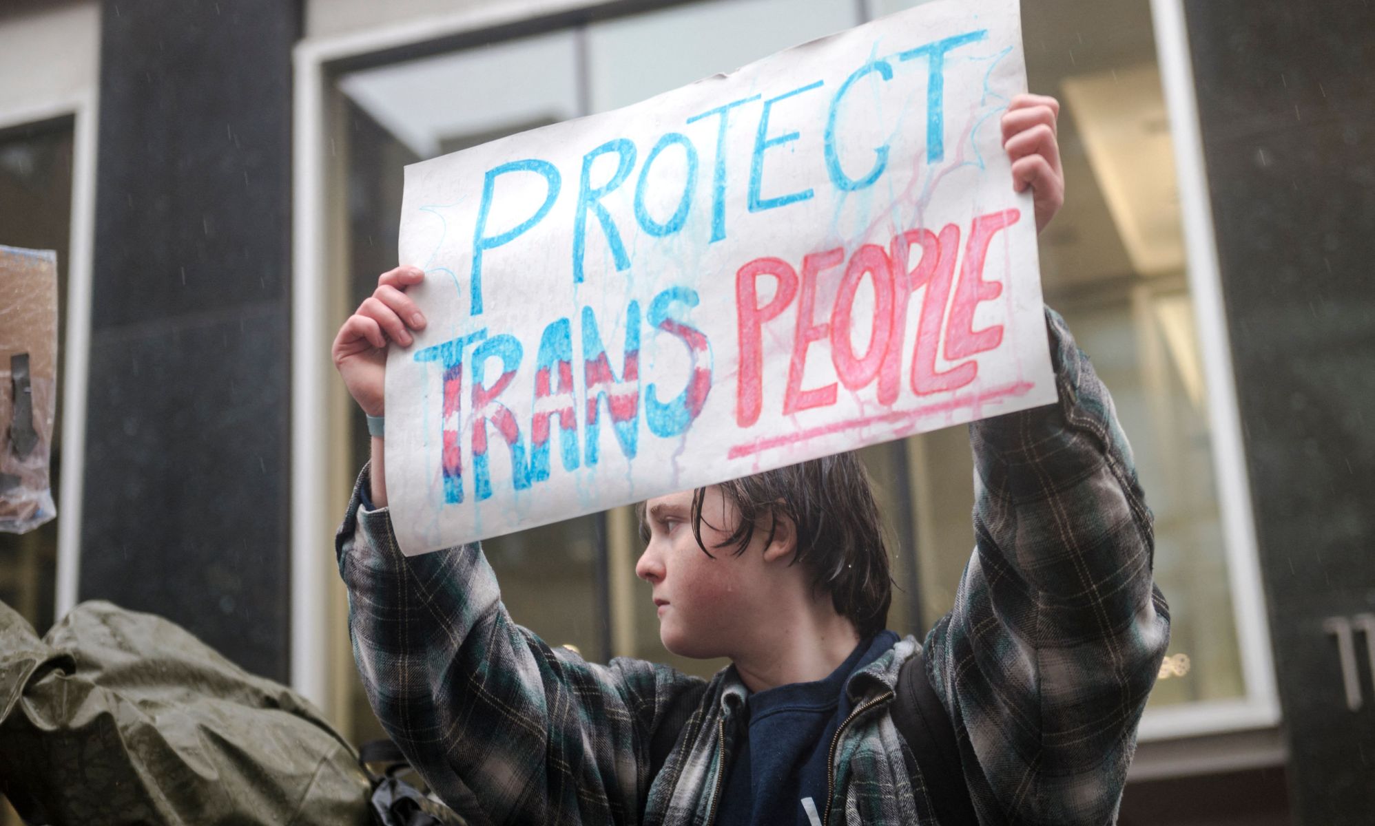 A person holds up a sign reading &quot;Protect trans people&quot; during a protest in support of the trans community held up LGBTQ+ people and allies