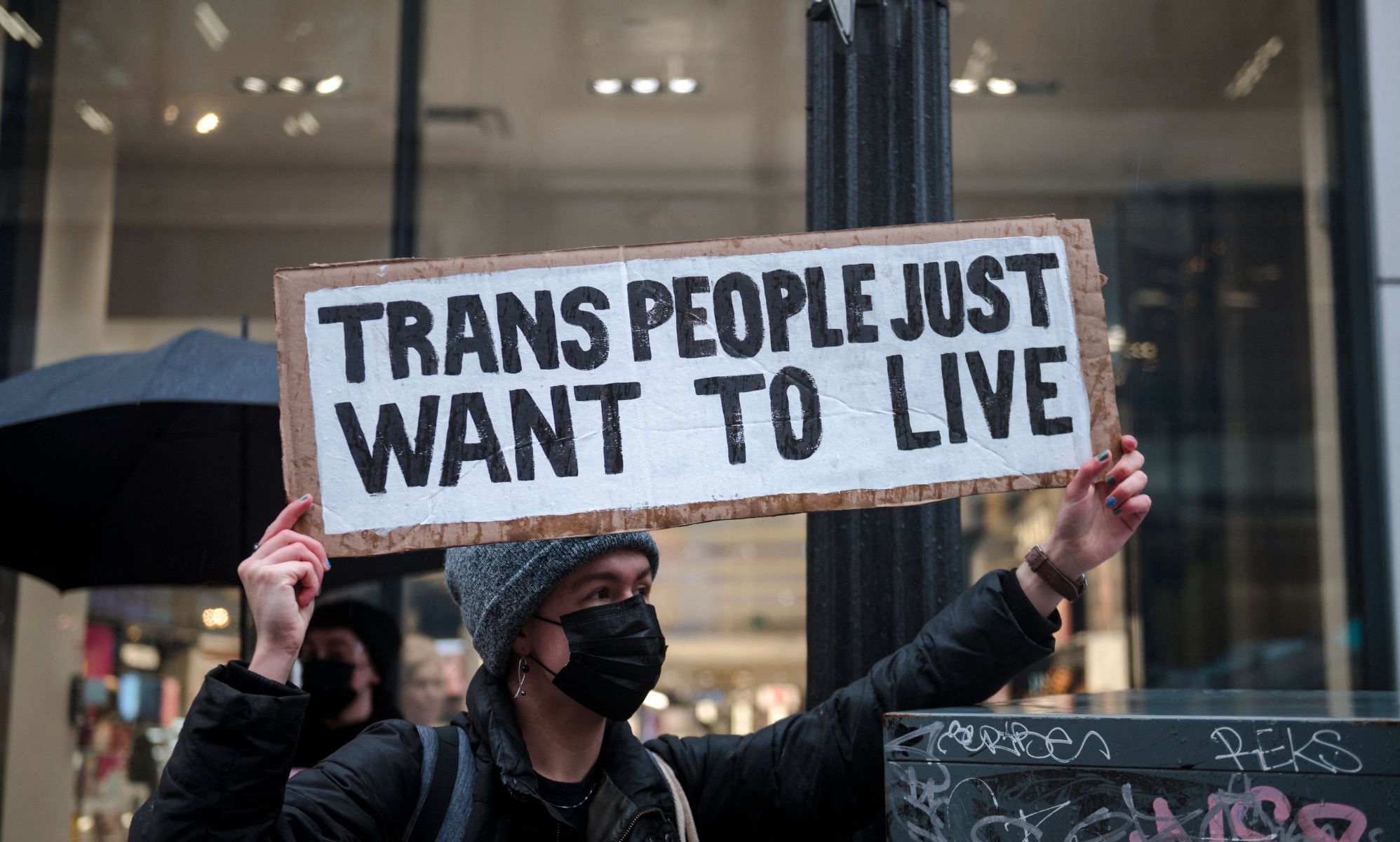 A person holds up a sign reading &quot;Trans people just want to live&quot; during a protest in support of the trans community held up LGBTQ+ people and allies