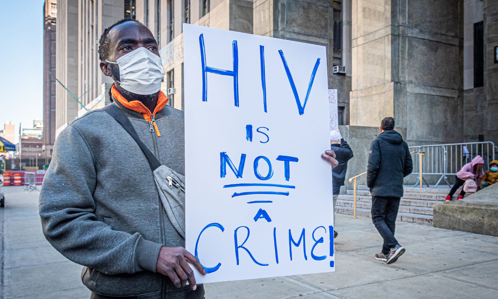 A man holds a sign reading &quot;HIV is not a crime&quot;