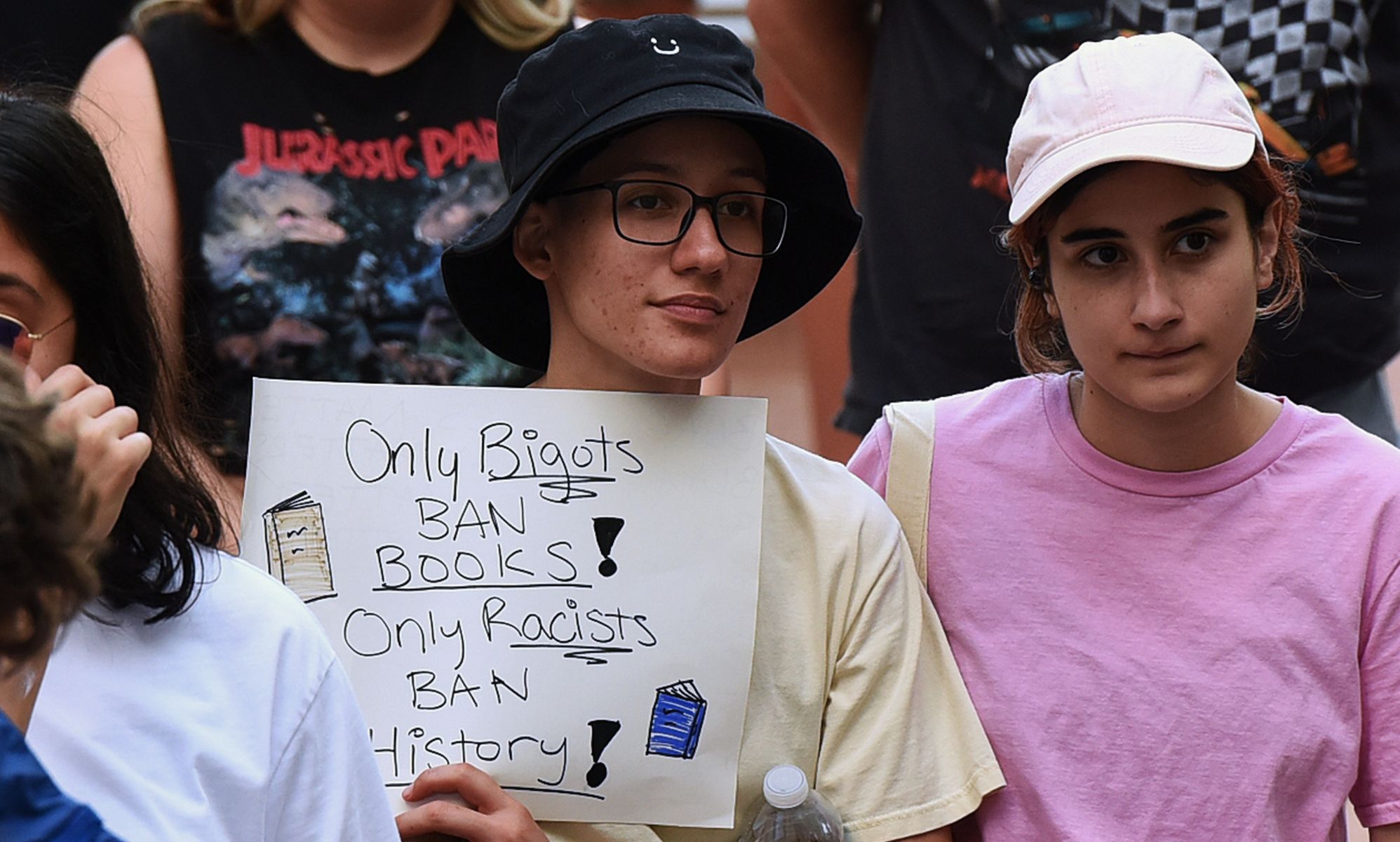 A person holds a sign reading &quot;only bigots ban books, only racists ban history.&quot;