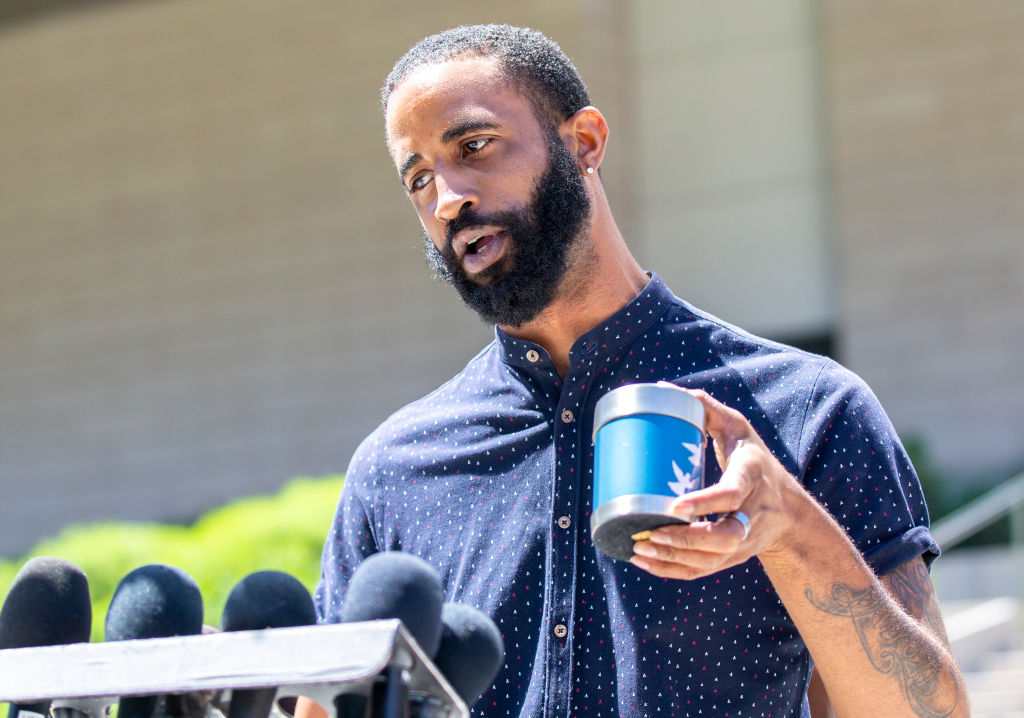 Cory McLean speaks to reporters and holds the ashes of his best friend, Gemmel Moore, 26. 
