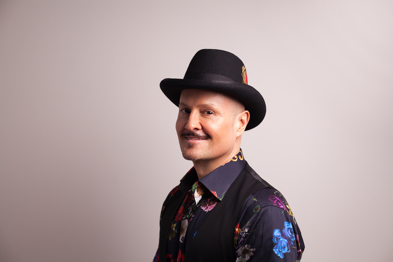 Paul Burston in a headshot. He is pictured wearing a hat.