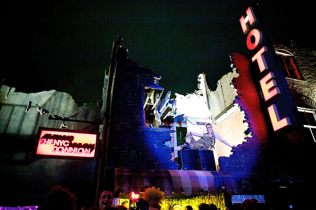 A crumbling, dilapidated building with a huge hole int he front, a hotel sign to the side 