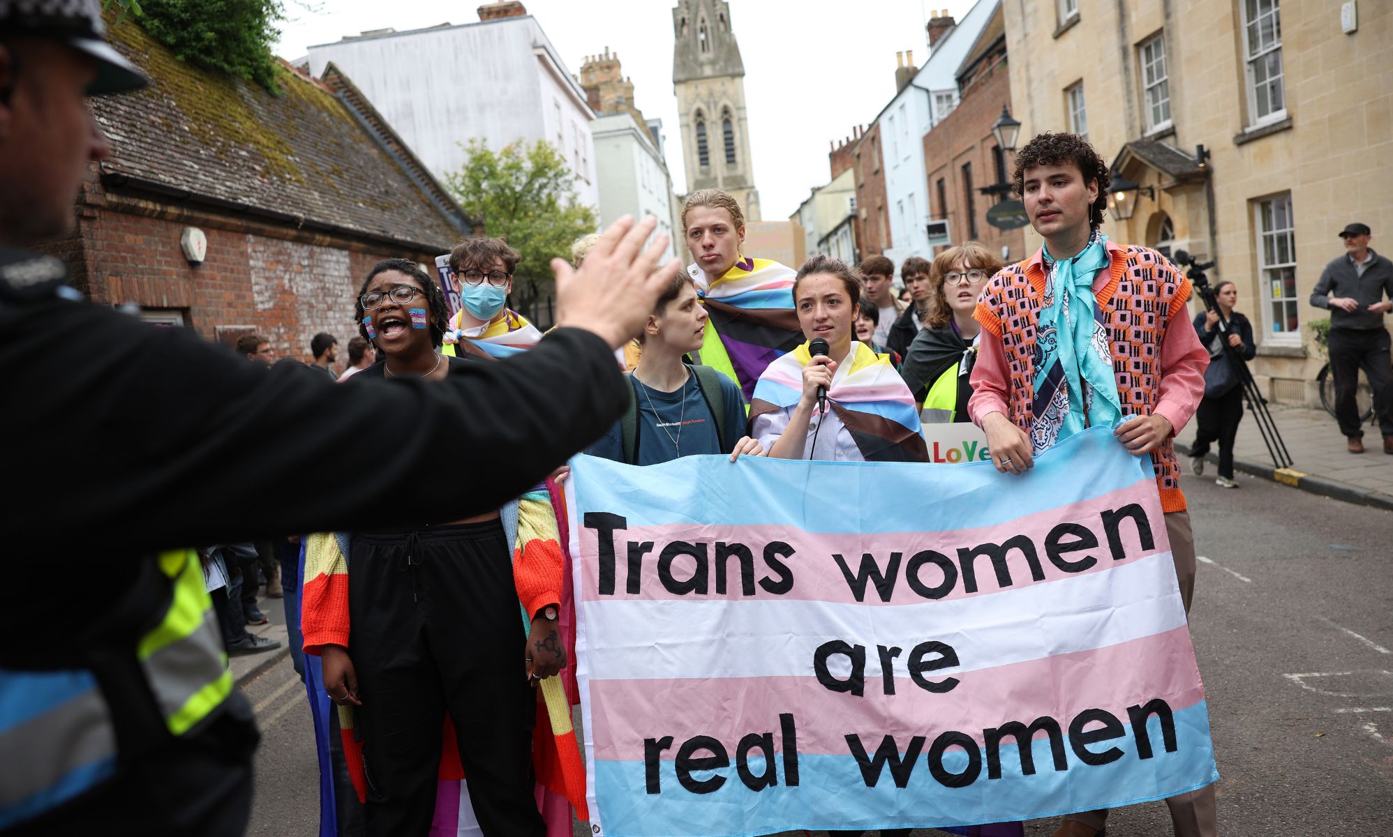 Trans rights advocates hold up a sign reading 