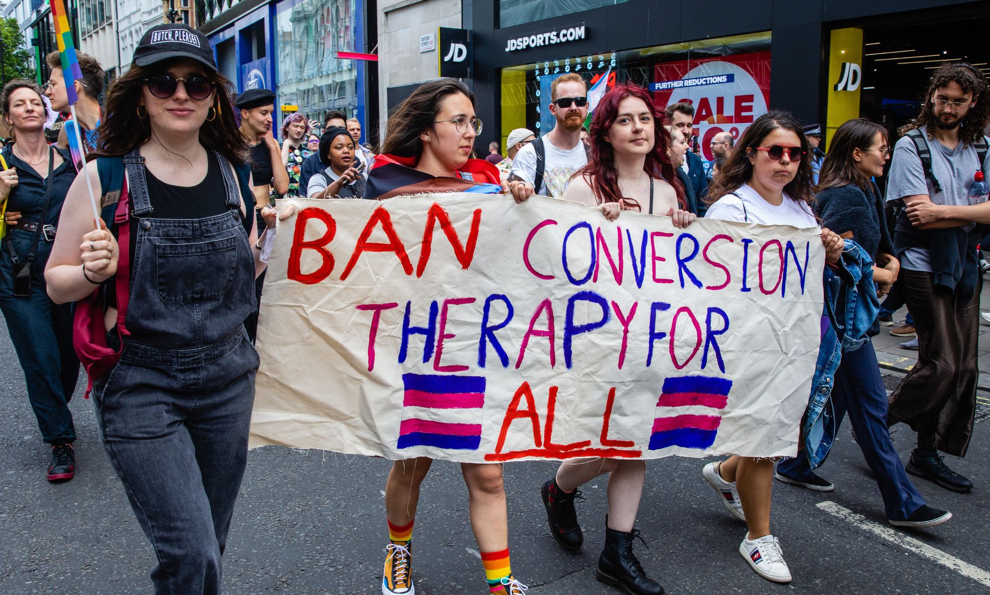 Activists hold a sign reading &quot;ban conversion therapy for all.&quot;