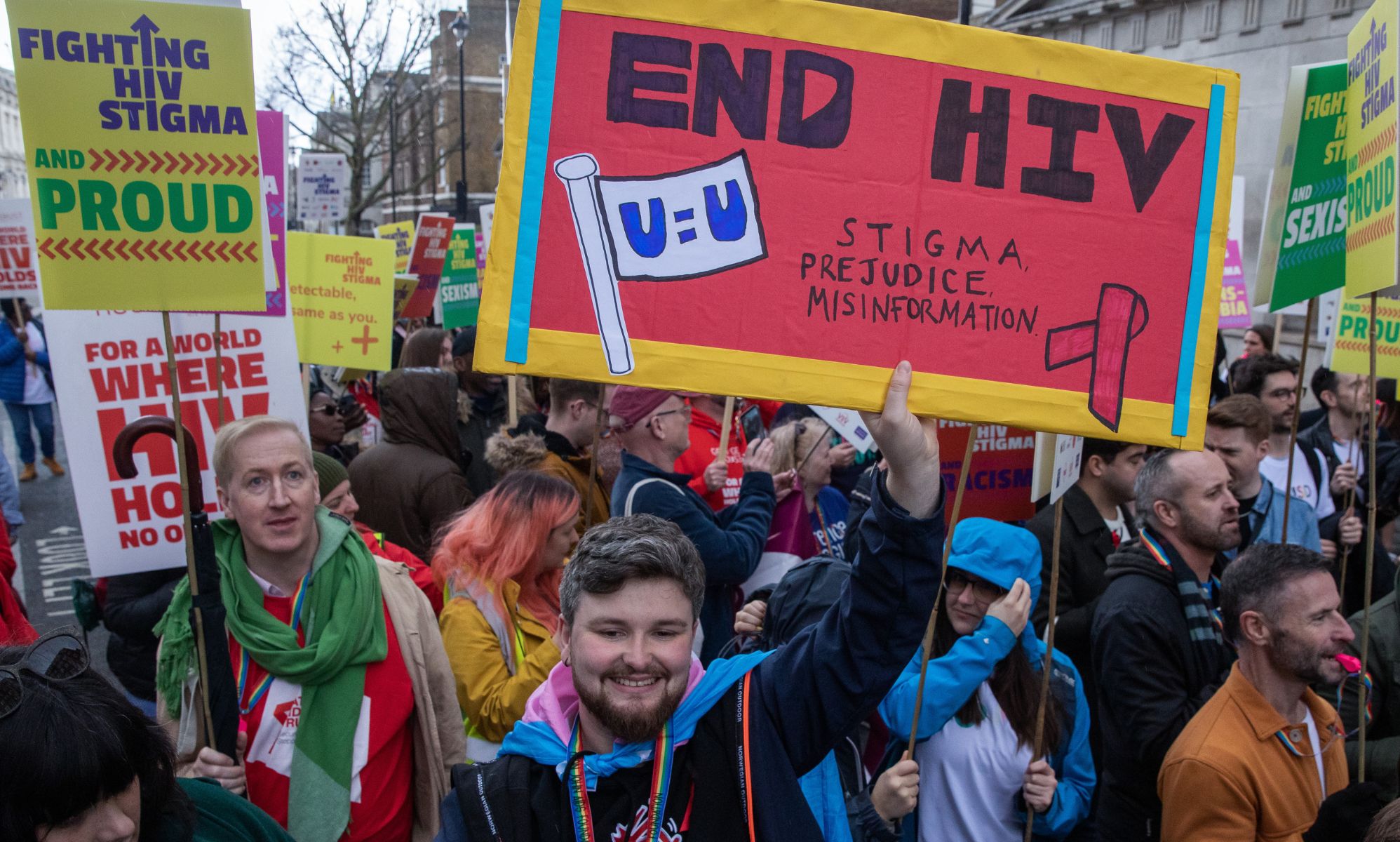 Protestors at a sexual health protest hold signs reading &quot;end HIV, stigma, prejudice, misinformation.&quot;